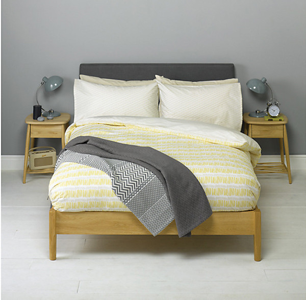 Chiếc giường gỗ có chăn đệm màu vàng nhạt kẻ sọc
