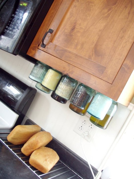 Các hũ thuỷ tinh đựng gia vị được treo ở phần mặt dưới của tủ bếp cũng là một ý tưởng hay cho việc lưu trữ đồ đạc tiết kiệm diện tích cho khu bếp