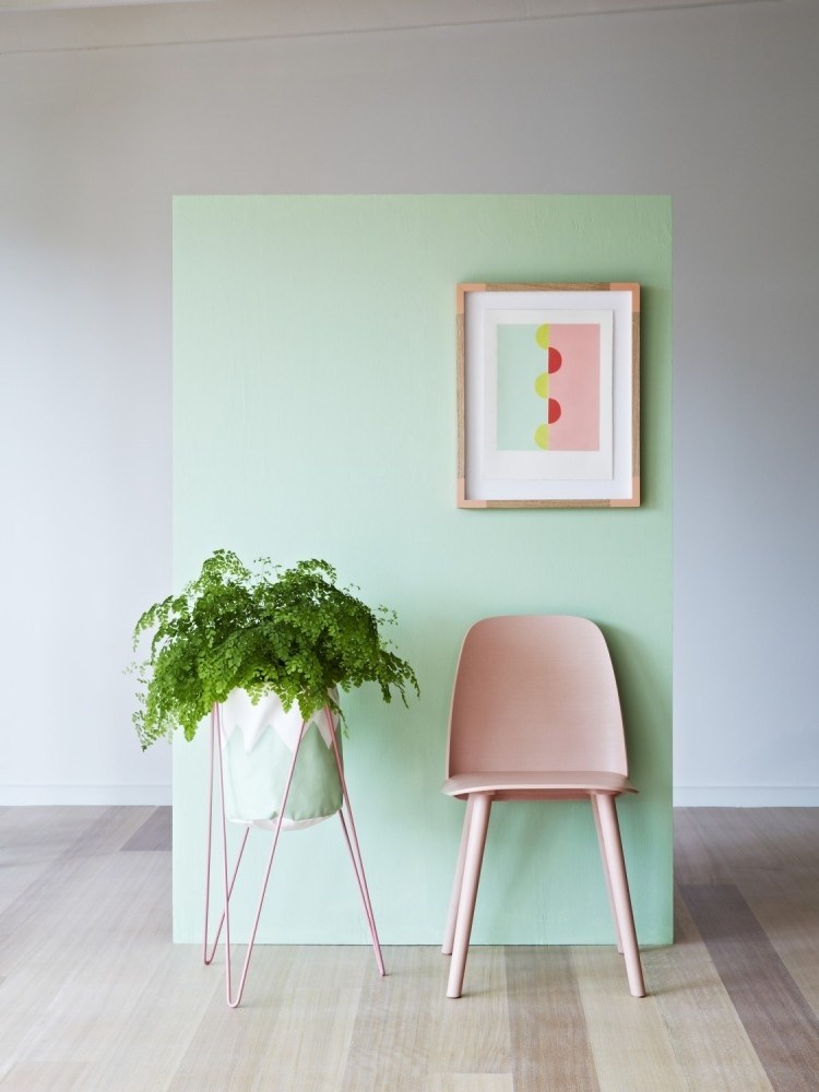 Chiếc kệ kim loại với phần thân đỡ ở dưới được sơn màu hồng pastel ​ kết hợp thêm bức tường xanh và ghế ngồi bên cạnh