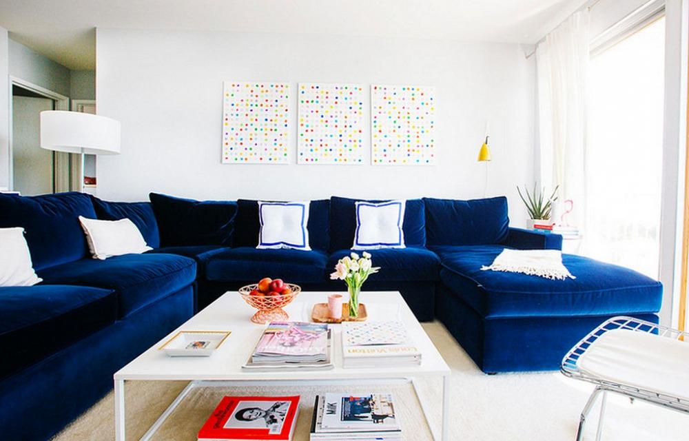Phòng khách với bộ sofa lớn bọc nhung màu xanh navy đậm nổi bật kết hợp bàn trà giản dị