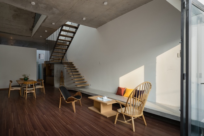 Ngôi nhà được thiết kế mộc mạc mang chất công nghiệp với trần bê tông, ​ bậc ngồi phòng khách cũng là nhịp dẫn lên cầu thang