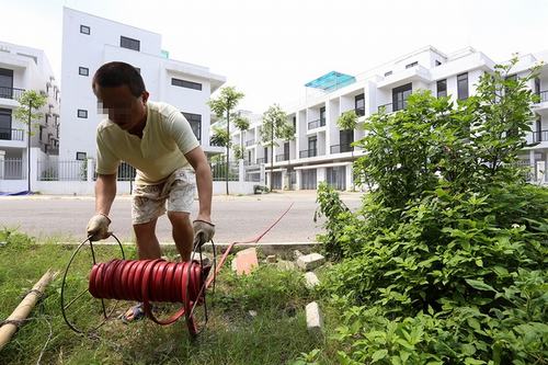 Gần 2 năm nay kể từ khi bàn giao, khu biệt thự không hề có nước sạch,  người dân phải dùng ống nước dài cả trăm mét, luồn qua một hàng rào thép gai  ​để mua nước từ một hộ dân bên xóm Giáp Tứ hay các khu dân cư ven sông Sét