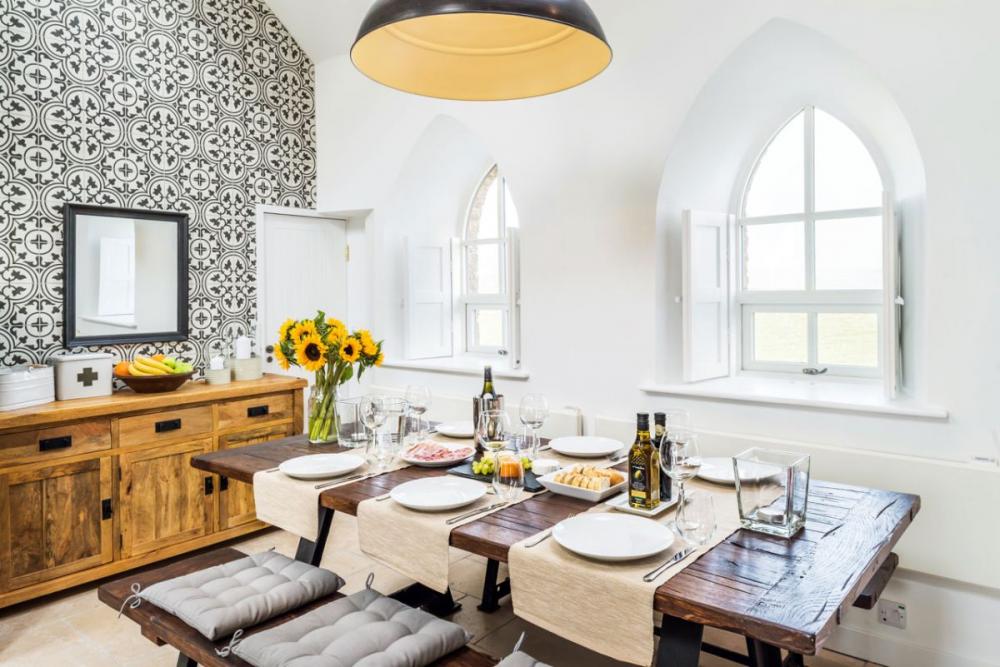 Bàn ăn với thiết kế áp sát khu vực bếp, dạng bàn hình chữ nhật bằng gỗ phổ biến,  ​2 ghế băng được đặt theo chiều dọc bàn đậm chất đồng quê
