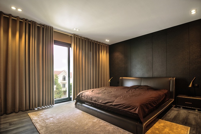 Phòng ngủ được thiết kế tối giản với tone màu trầm, cửa kính lớn cung cấp ánh sáng và tầm nhìn ra khung cảnh bên ngoài