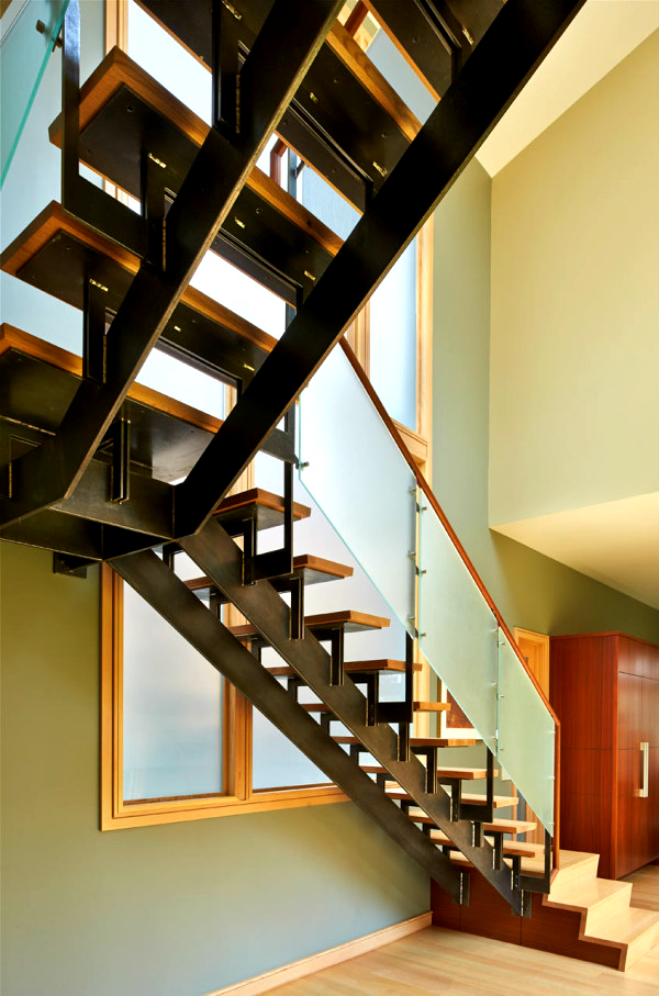 Cầu thang dẫn lối tầng 1 đặt sát cửa cũng được sử dụng bộ ba chất liệu gồm gỗ, kim loại và kính cường lực