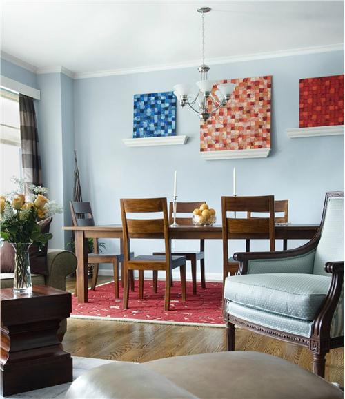 Tường và ghế ngồi màu xanh da trời nhạt, bàn ghế gỗ nâu nhạt như một bối cảnh yên tĩnh cho các phụ kiện màu xanh và màu đỏ đậm trên tường nổi bật đầy ấn tượng