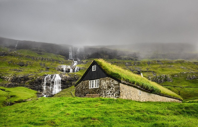 Ngôi nhà làm bằng đá và lợp mái cỏ nằm bên cạnh một thác nước thuộc hòn đảo đẹp như tranh vẽ của Streymoy,Saksun, quần đảo Faroe