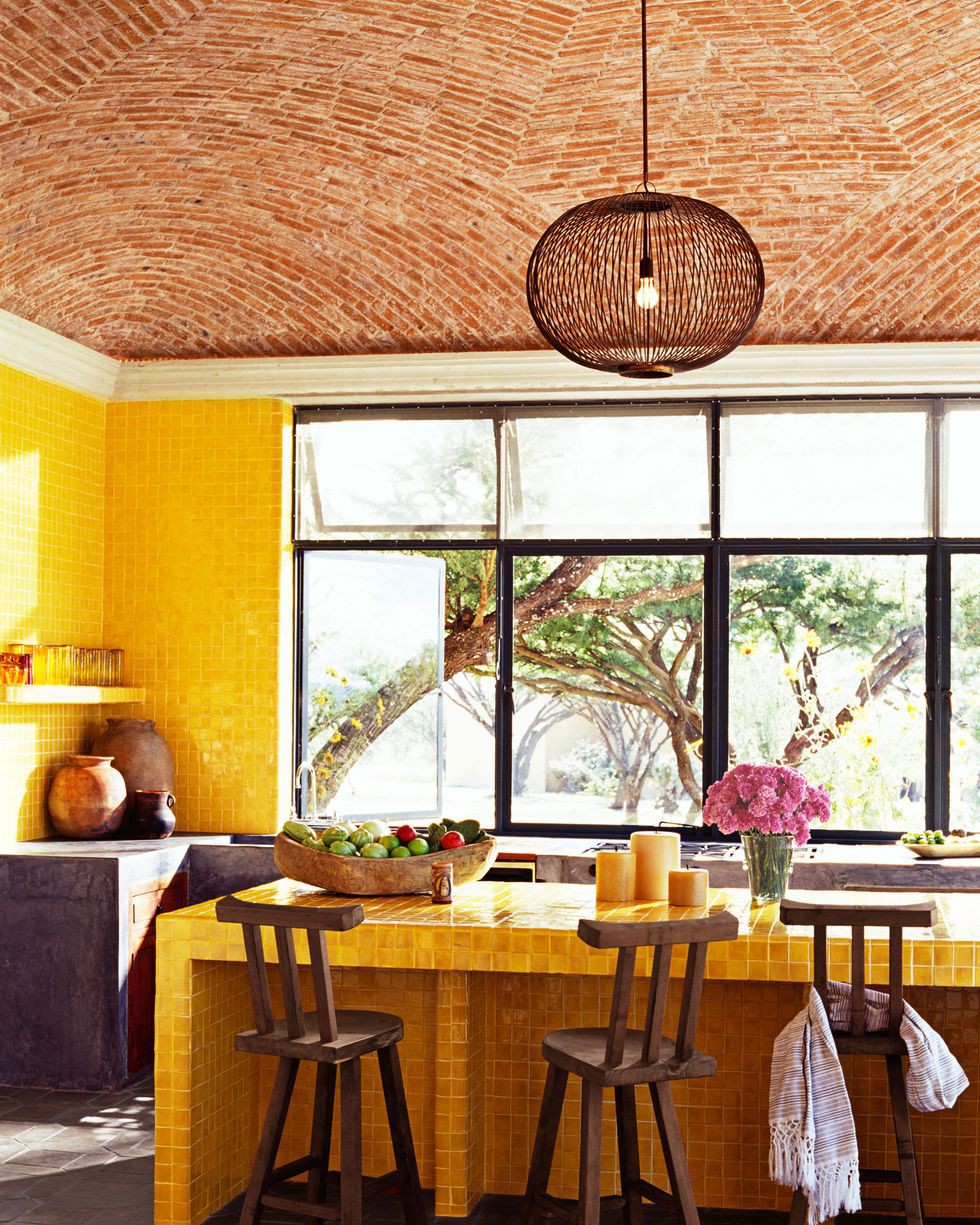 Điểm nhấn của phòng bếp màu vàng chủ đạo chính là những chiếc ghế gỗ mộc mạc.