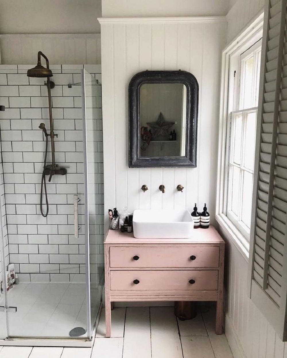 Tủ gỗ màu hồng phong cách vintage tạo điểm nhấn sinh động cho phòng tắm tông màu trắng sáng chủ đạo. 