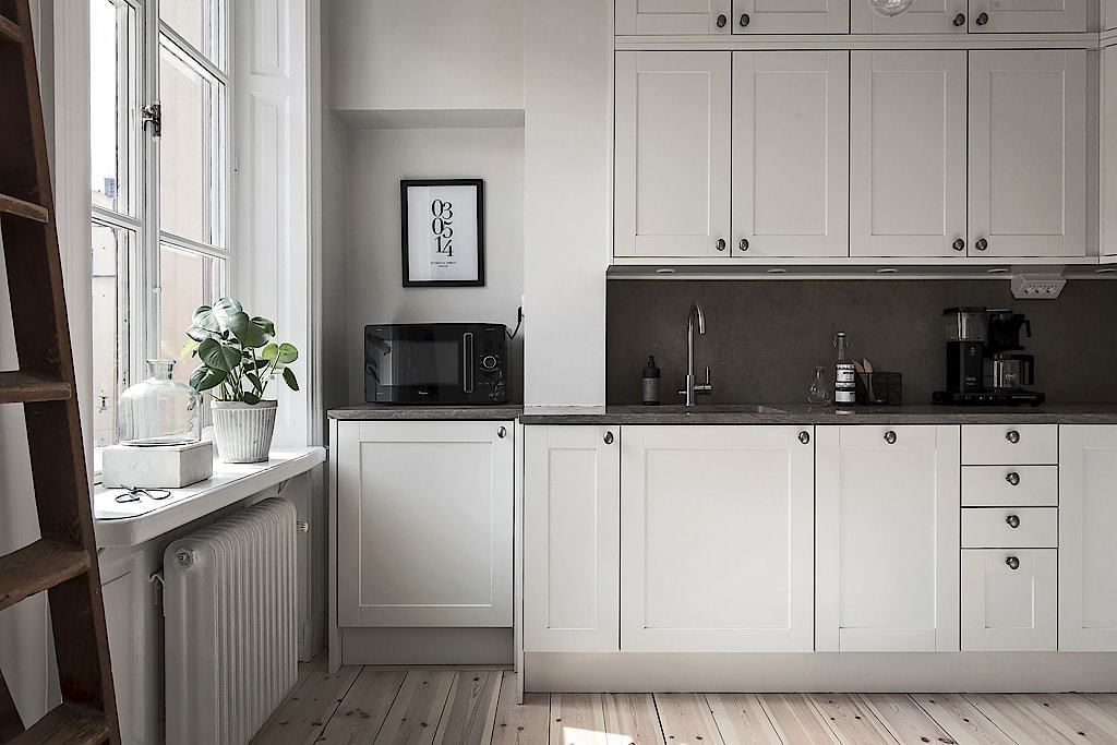 Hình ảnh phòng bếp thoáng sáng với hệ tủ lưu trữ ẩn màu trắng