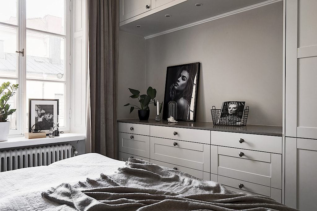 Hình ảnh một vài khung ảnh đen trắng và chậu cảnh xanh mát giúp phòng ngủ màu trắng trở nên sinh động, tươi mới và tràn đầy năng lượng.