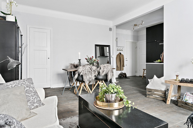 Hình ảnh toàn cảnh phòng khách và khu vực ăn uống, nổi bật với phụ kiện trang trí mạ đồng trên bàn trà màu đen