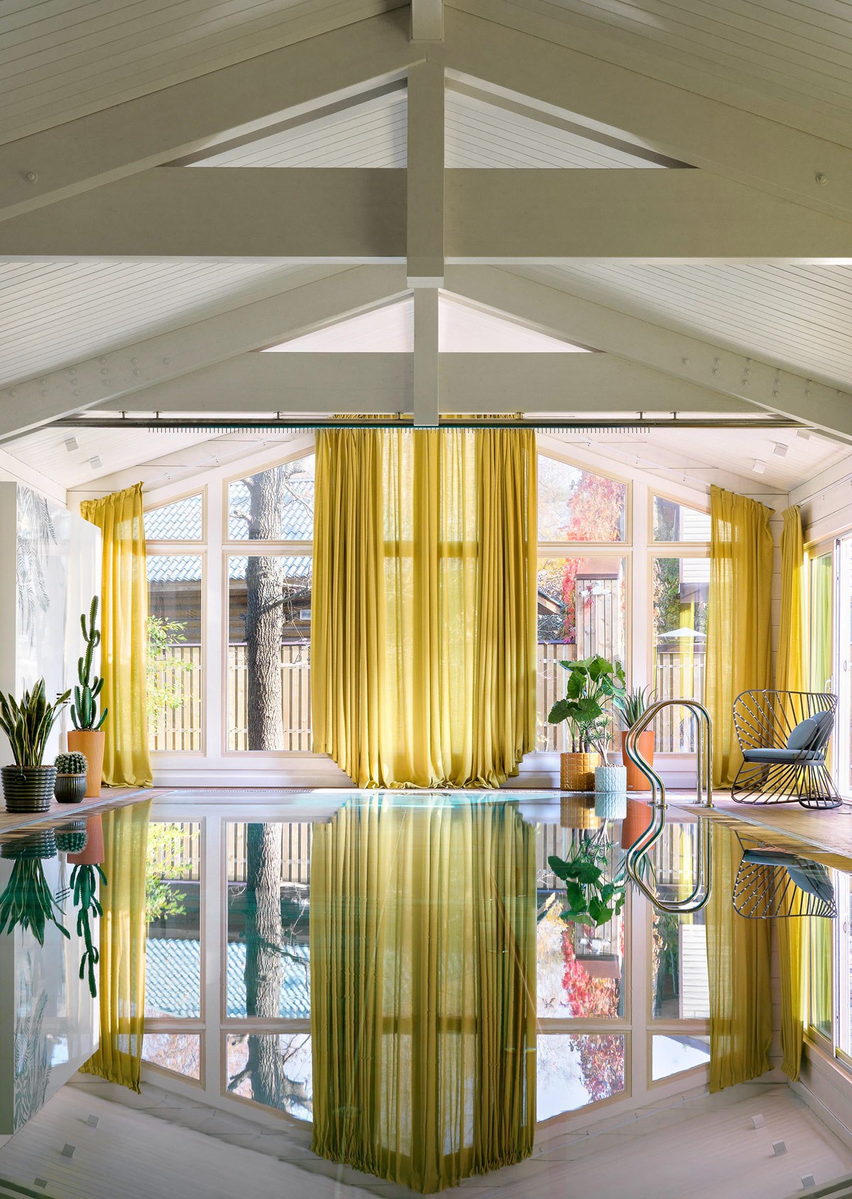 Hình ảnh hồ bơi bên trong ngôi nhà rực rỡ sắc màu, phản chiếu rèm cửa màu vàng chanh