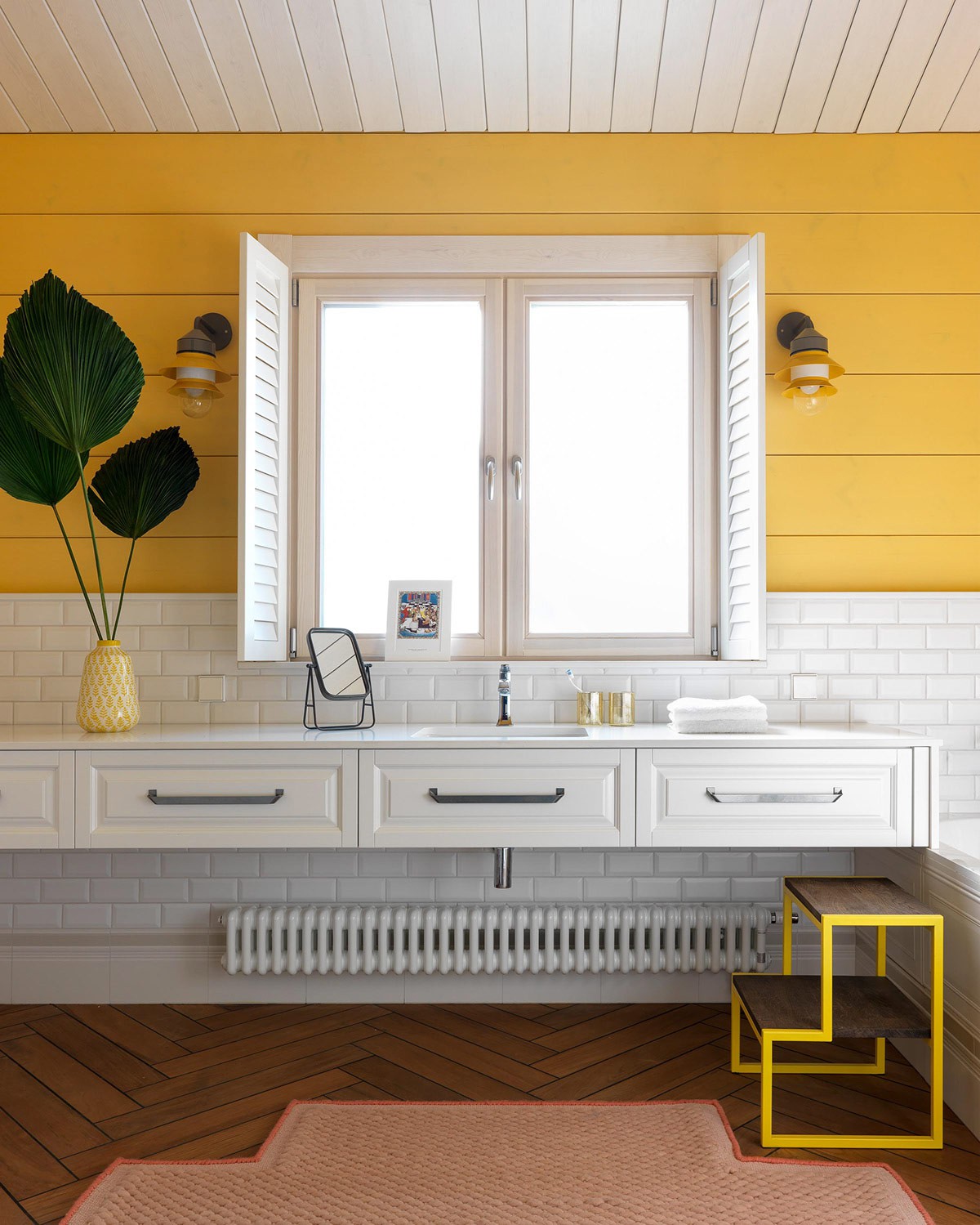 Hình ảnh một góc phòng tắm với tường sơn vàng, cửa sổ kính, ngăn kéo lưu trữ màu trắng