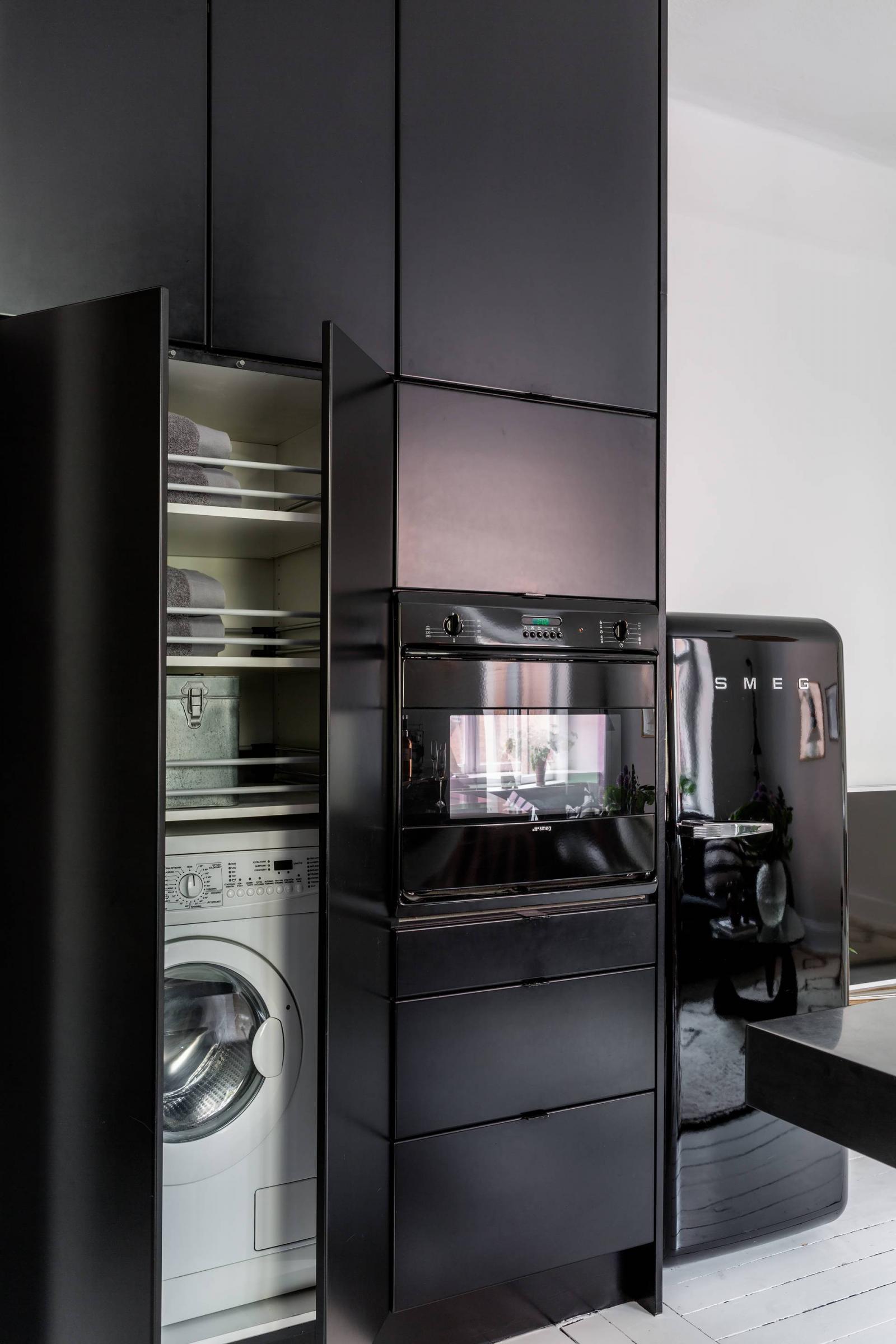 Hình ảnh cận cảnh hệ tủ bếp màu đen sang trọng, cá tính, nơi đặt máy giặt, tủ lạnh