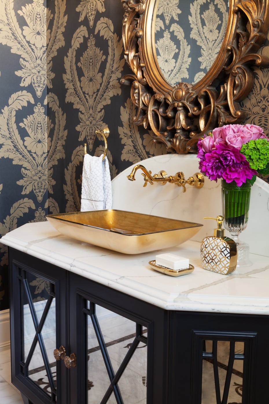 Phòng tắm cổ điển với giấy dán tường màu đen chủ đạo, bồn rửa bằng đồng sáng bóng, lọ hoa trang trí