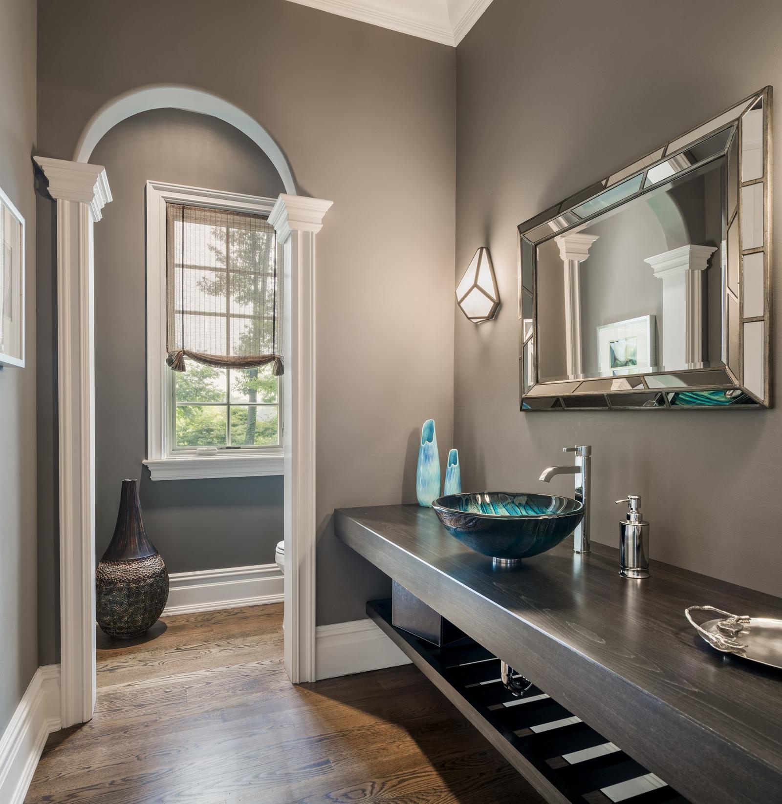 Hình ảnh phòng tắm thoáng sáng với khung cửa hình vòm, bồn rửa tay màu xanh ngọc, bộ bình trang trí, khung gương lớn