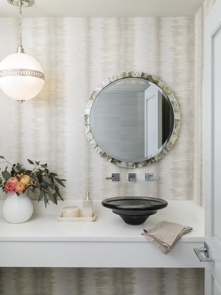 Hình ảnh bồn rửa tay màu đen trong phòng tắm hiện đại, phía trên là gương tròn, bên cạnh là bình hoa trang trí