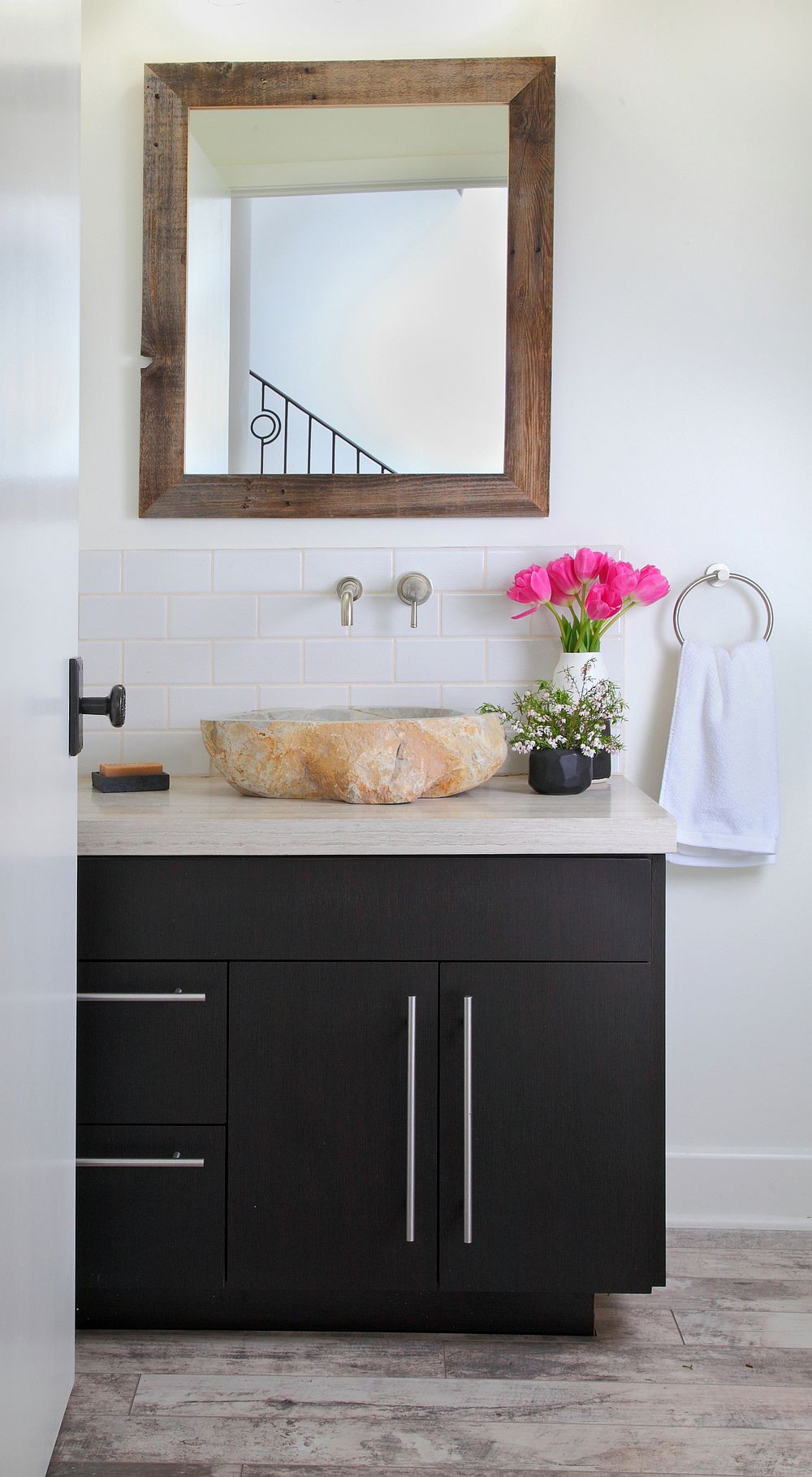 Hình ảnh phòng tắm đẹp với bồn rửa làm từ đá nguyên khối, gường treo khung gỗ, lọ hoa tuy líp, tủ sơn đen