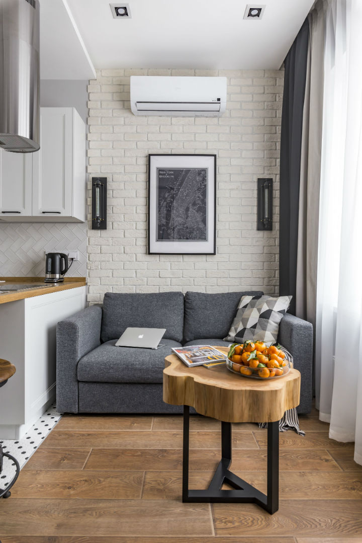 Hình ảnh không gian tiếp khách trong căn hộ 25m2 được gói gọn với sofa đơn, bàn trà mặt gỗ nguyên khối, tranh treo tường đơn giản.