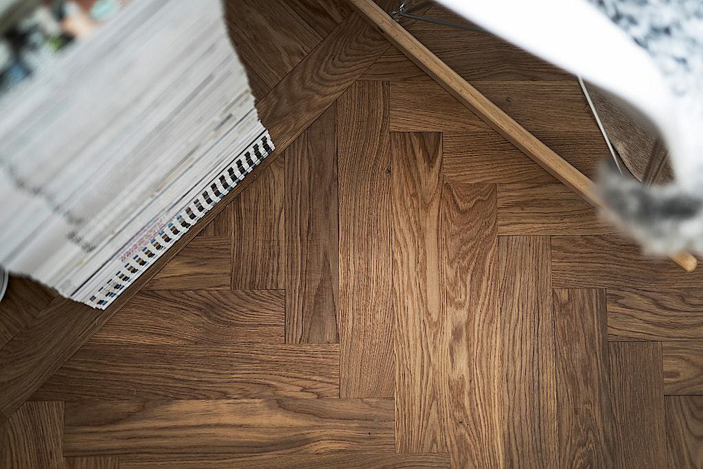 Hình ảnh toàn bộ sàn căn hộ 36m2 được lát gỗ tự nhiên sẫm màu giúp cân bằng bảng màu và tạo chiều sâu cho không gian nhà