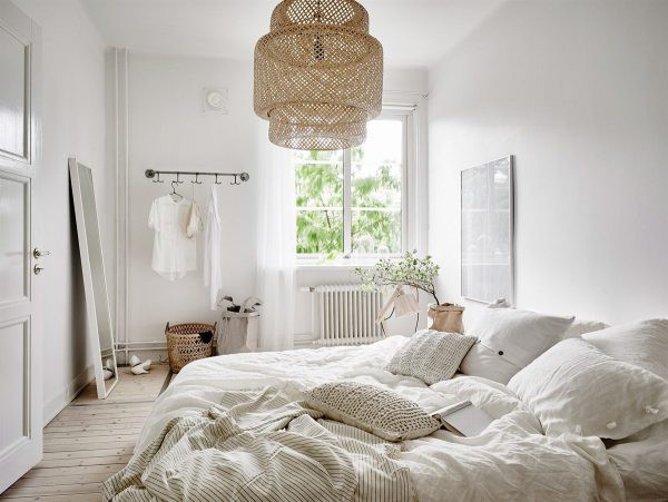 Hình ảnh phòng ngủ phong cách Bắc Âu với chăn gối màu trắng, đèn thả làm bằng mây tự nhiên, cửa sổ kính, móc treo đồ