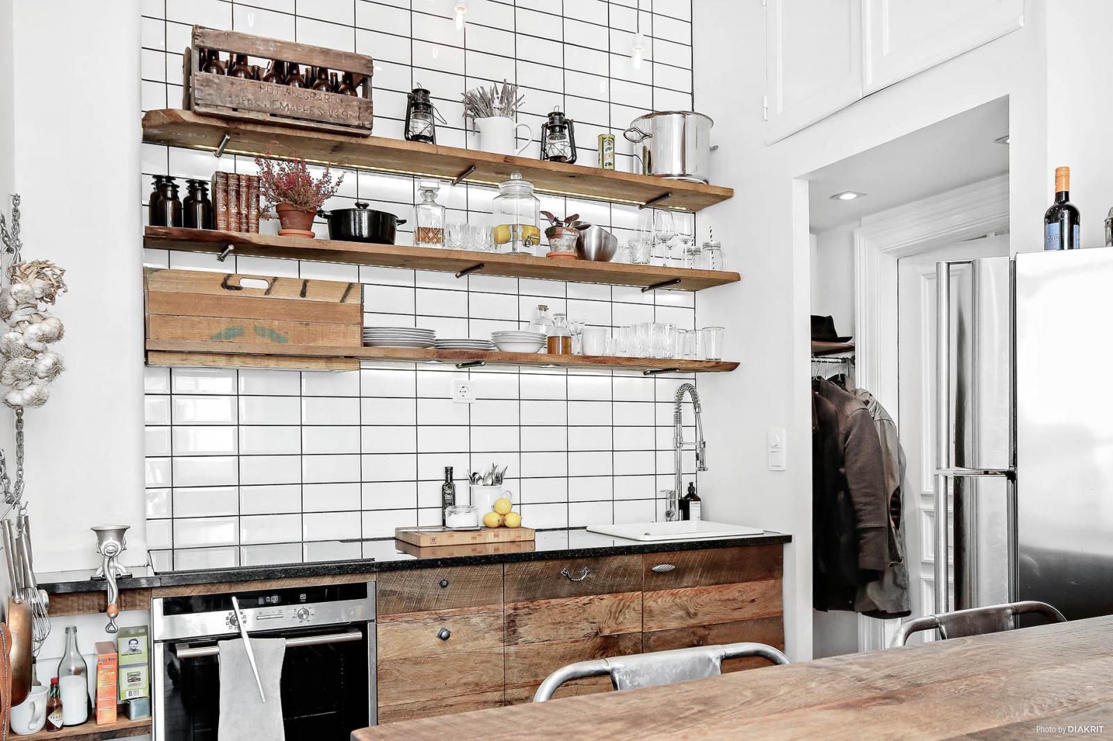 Hình ảnh cận cảnh bức tường ốp gạch men trong phòng bếp, kệ lưu trữ bằng gỗ