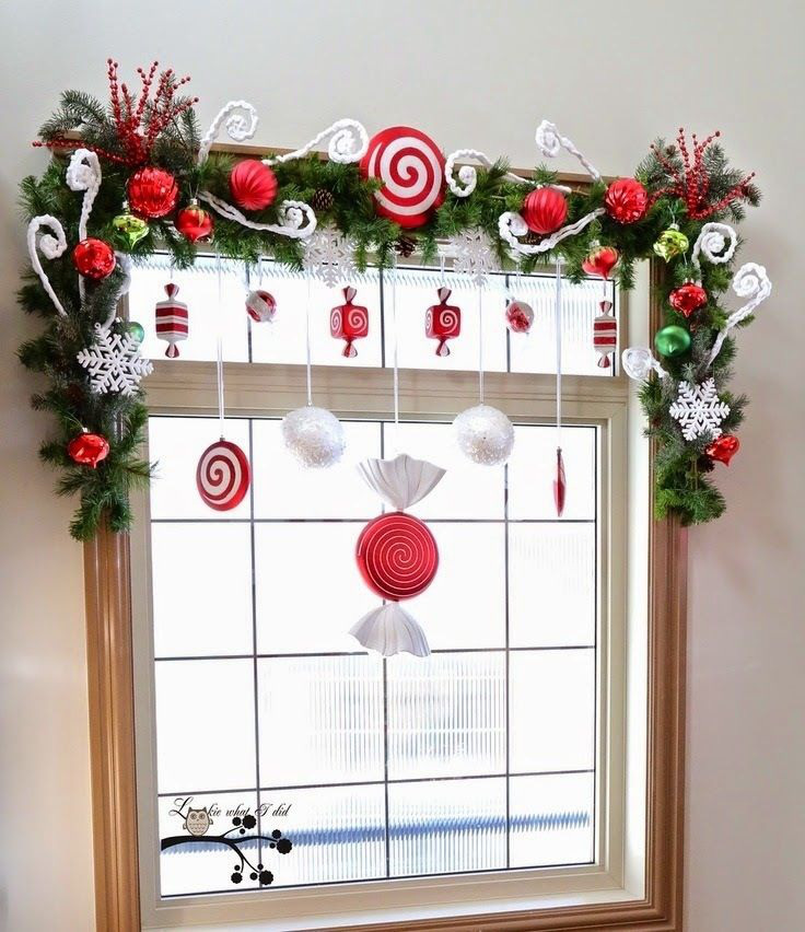Hình ảnh cửa sổ kính được trang trí với vòng hoa thường xanh, phụ kiện trang trí Giáng sinh màu đỏ ấm áp