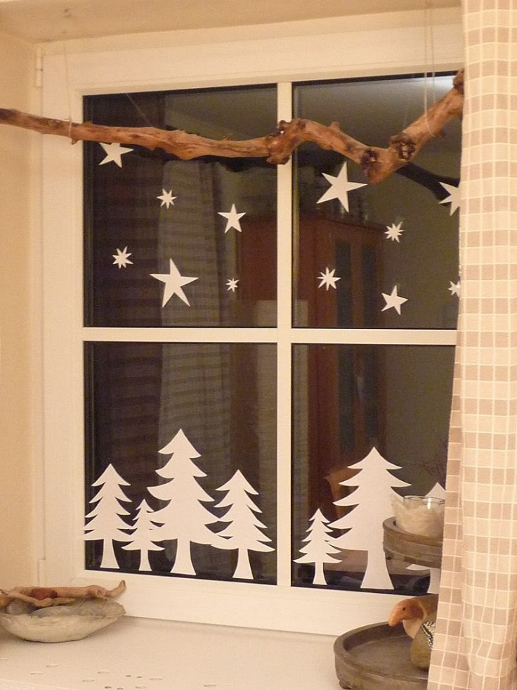 Hình ảnh cửa sổ được trang trí với những ngôi sao và cây linh sam được cắt từ giấy trắng.