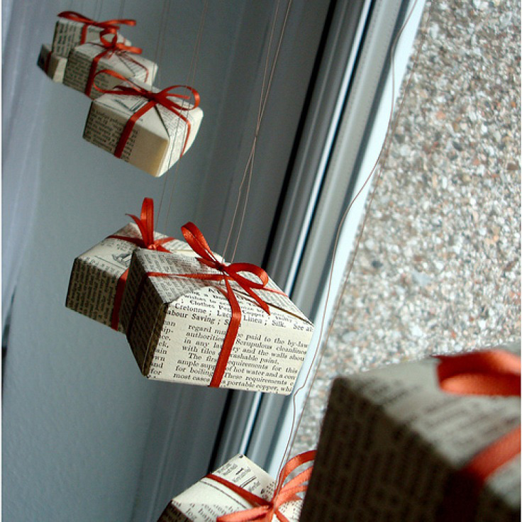 Hình ảnh những hộp quà nhỏ xinh gói trong giấy báo, buộc ruy băng đỏ trang trí cửa sổ kính