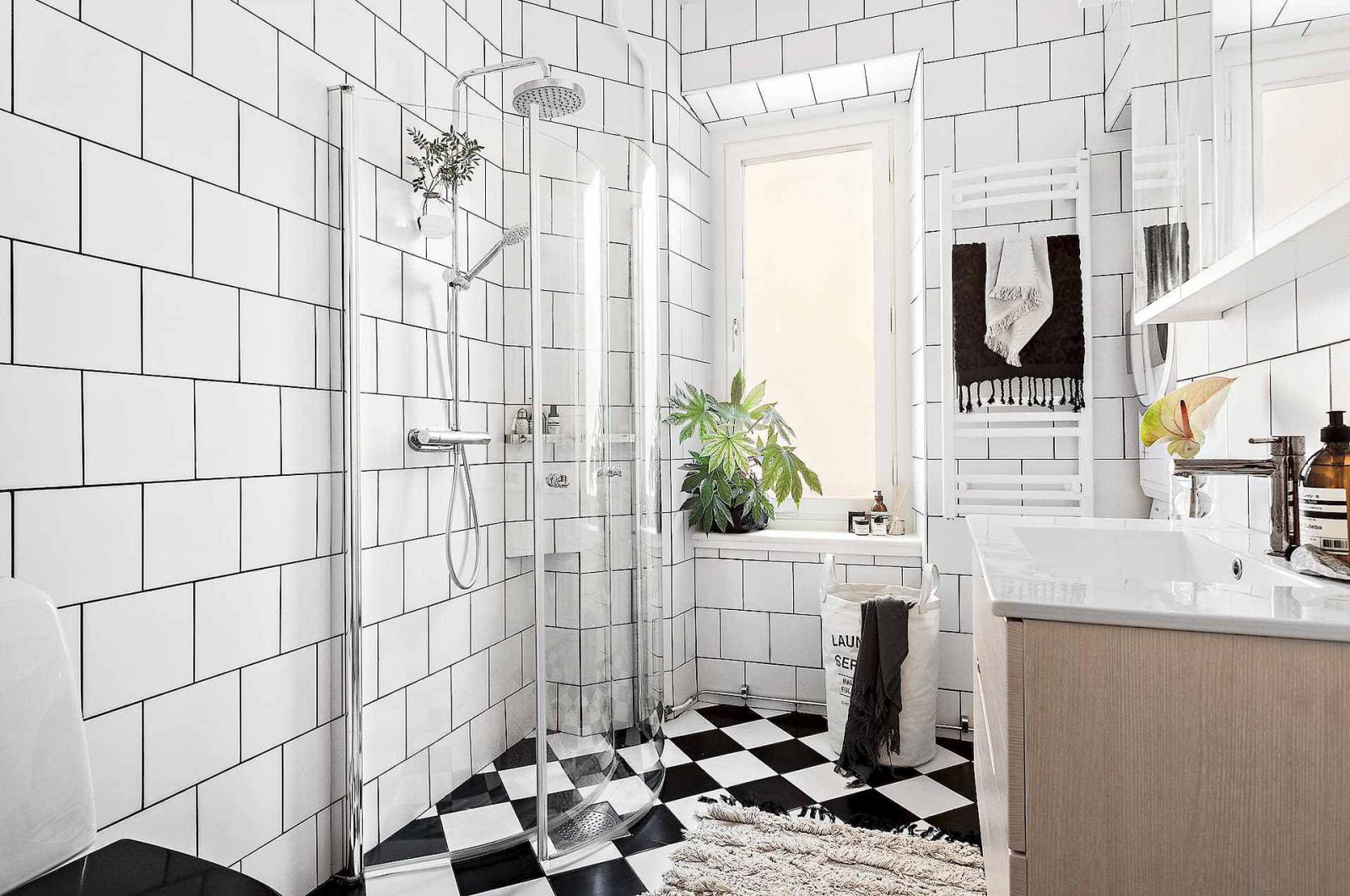 Hình ảnh phòng tắm sang trọng, sạch sẽ với tường ốp gạch trắng, sàn lát gạch đen - trắng