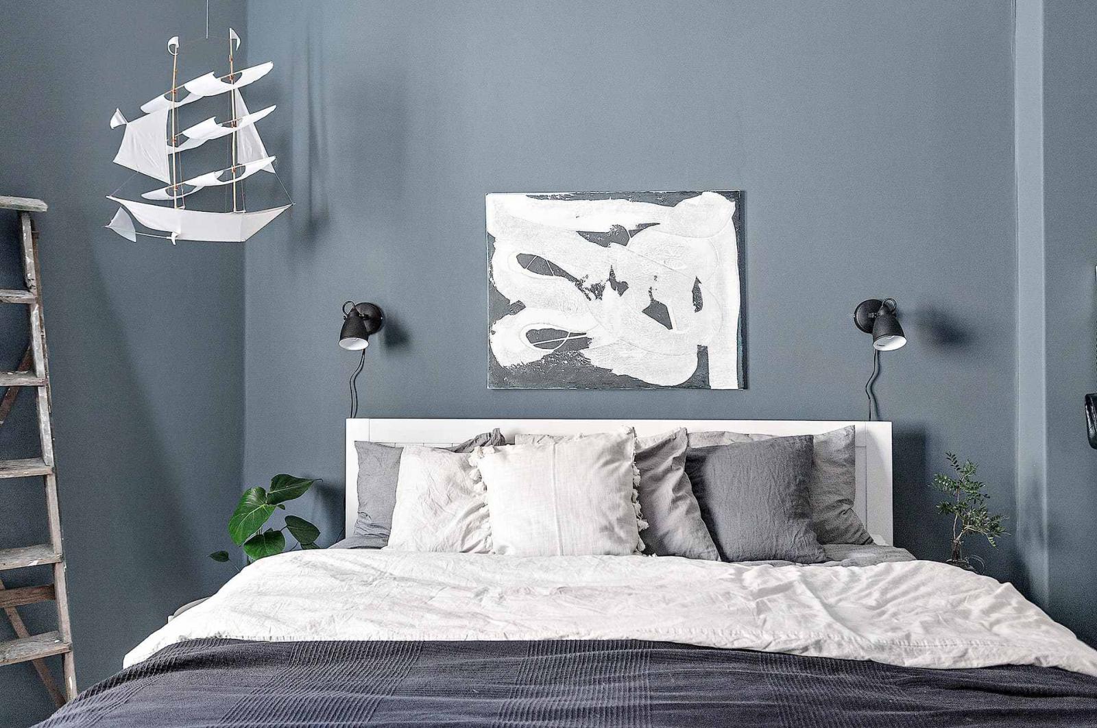 Hình ảnh phòng ngủ với bộ đôi đèn đầu giường, tranh treo nghệ thuật, mô hình thuyền buồm...tường sơn xanh