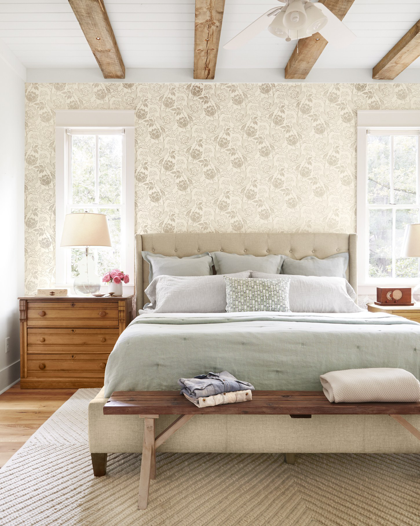 Hình ảnh phòng ngủ với giường nệm êm ái, cạnh đó là tủ ngăn kéo bằng gỗ, giấy dán tường đầu giường, dầm gỗ mộc mạc