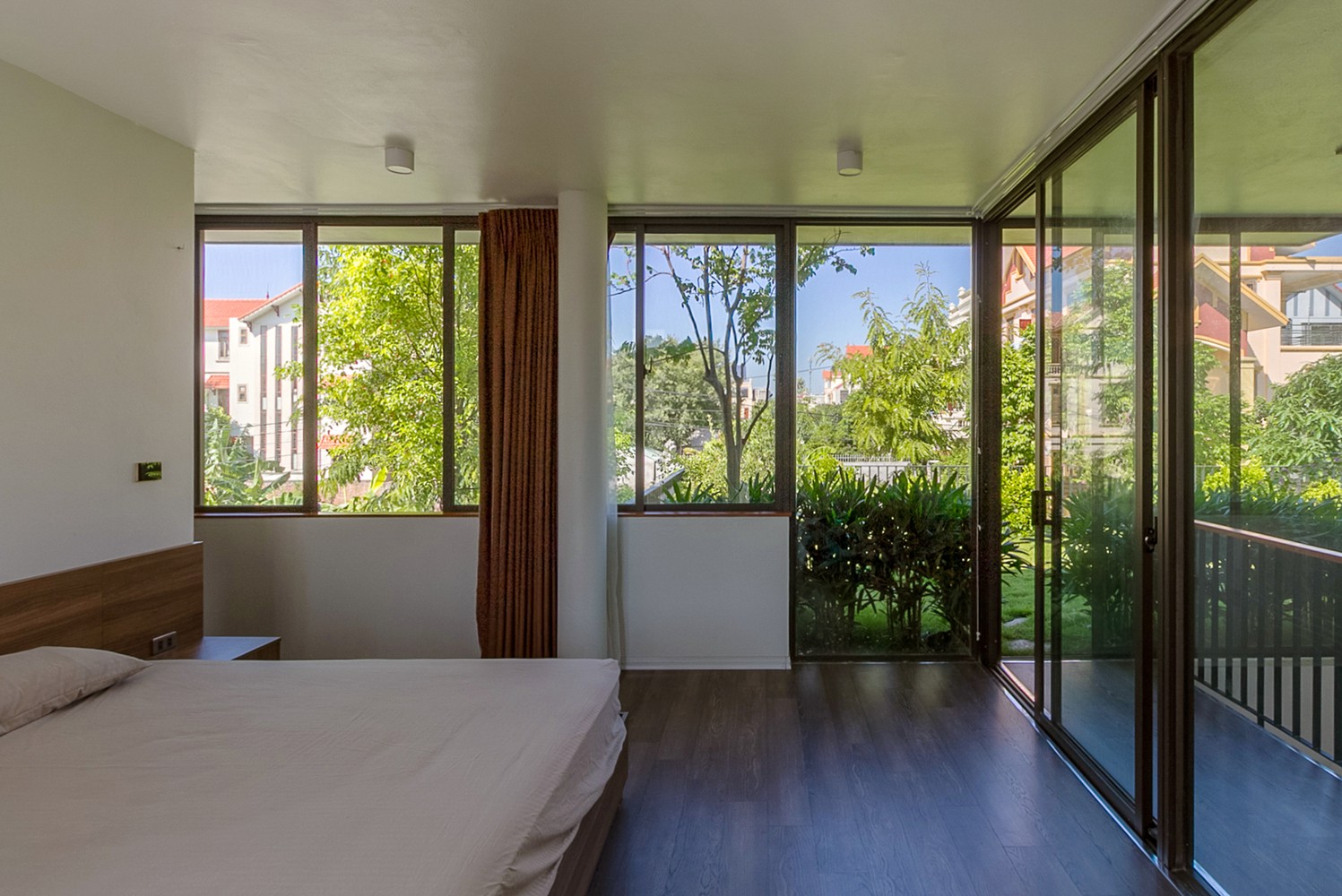 Hình ảnh phòng ngủ có thiết kế đơn giản với giường nệm màu trắng, cửa sổ kính, rèm cửa
