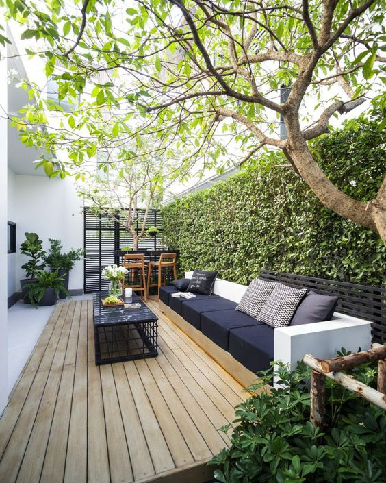 Hình ảnh mẫu thiết kế góc thư giãn lý tưởng nơi sân vườn với sàn ốp gỗ, tường cây xanh mát mắt.