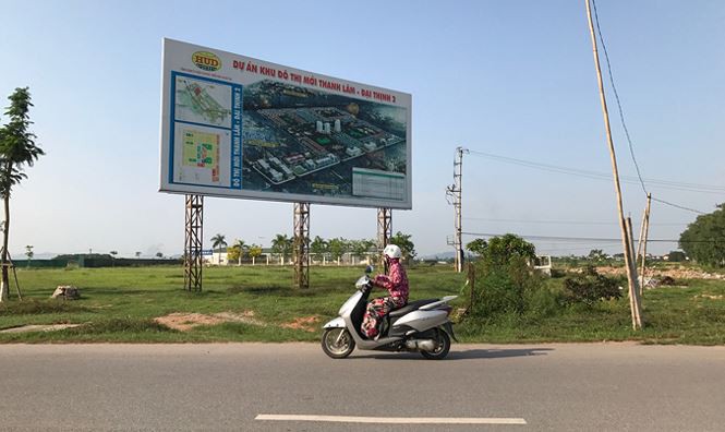 Hình ảnh một khu đất dự án nhà ở xã hội ở Thanh Trì, Hà Nội chậm triển khai, cạnh đó là đường nhựa xe cộ qua lại