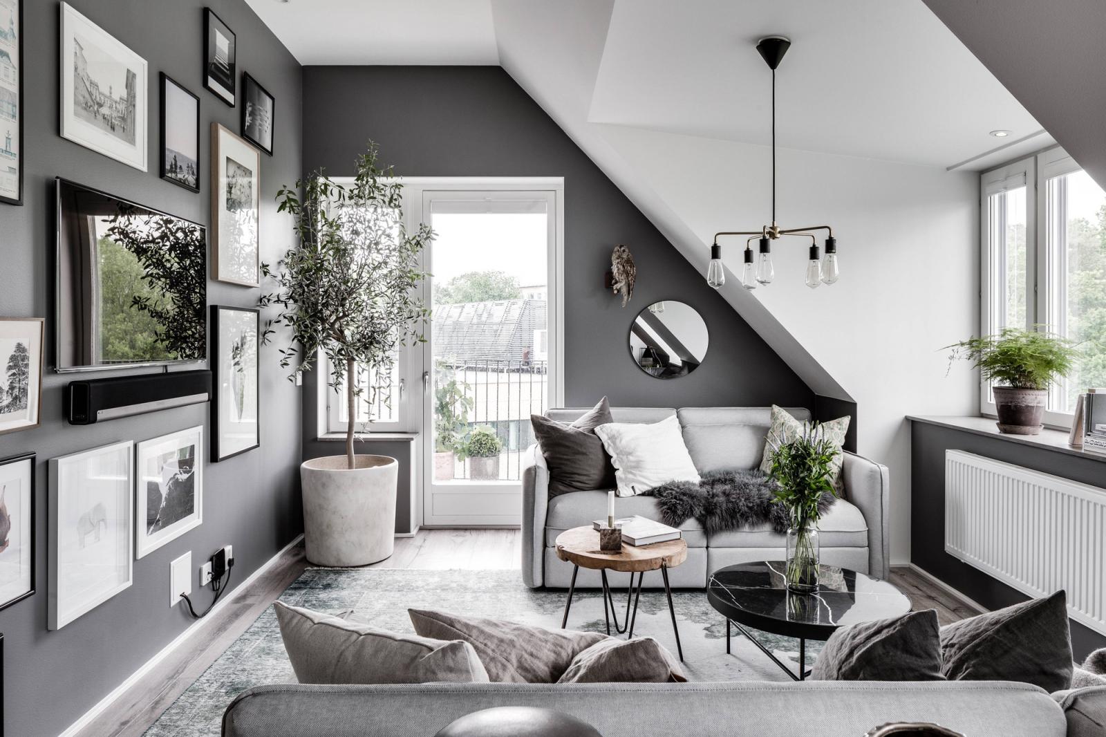 Hình ảnh phòng khách với tông màu xám trắng chủ đạo, sofa êm ái tranh treo tường, cây xanh trang trí