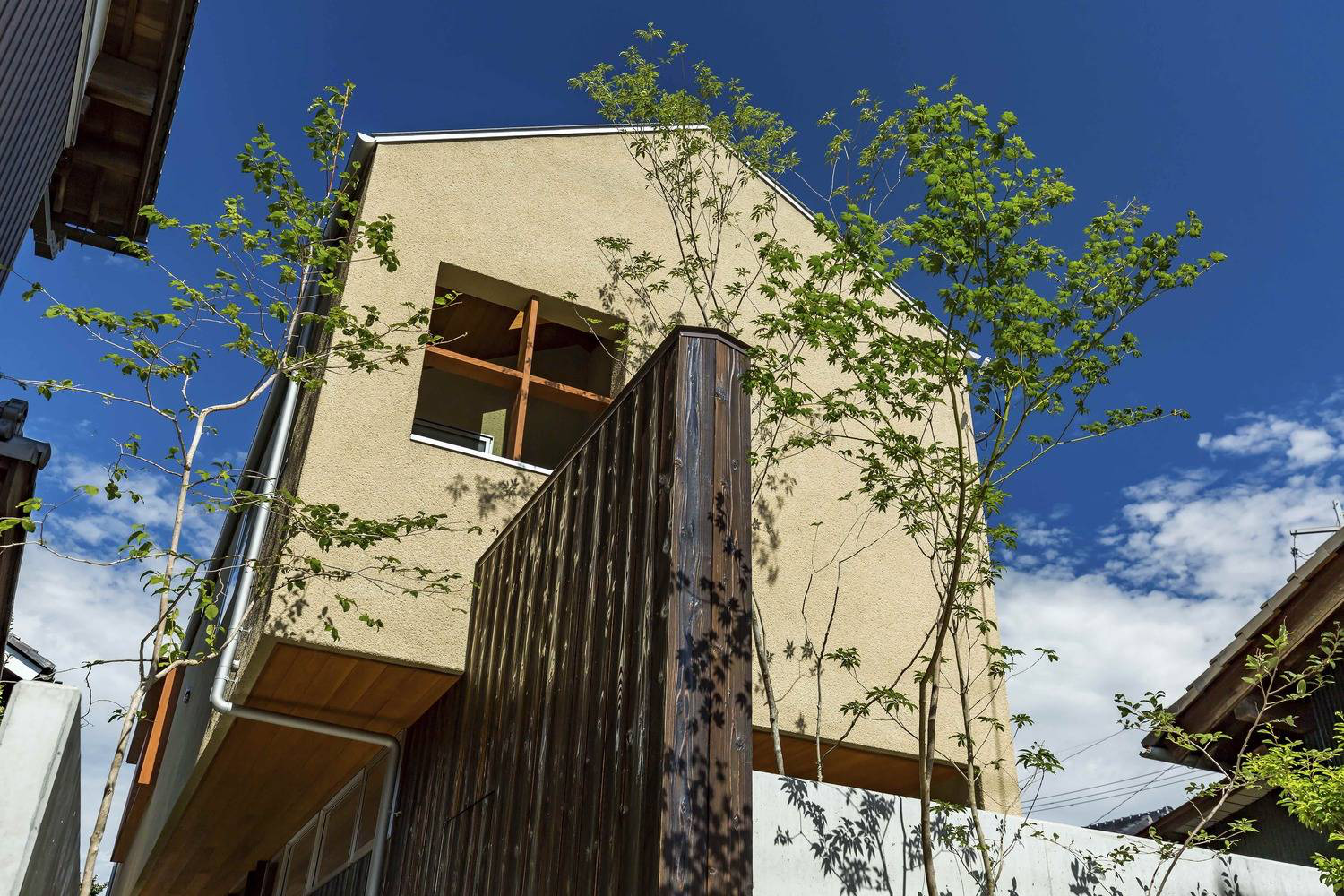 Hình ảnh cận cảnh vẻ ngoài ngôi nhà phố phong cách Nhật đơn giản với tường xi măng, khung cửa sổ gỗ, tường bao