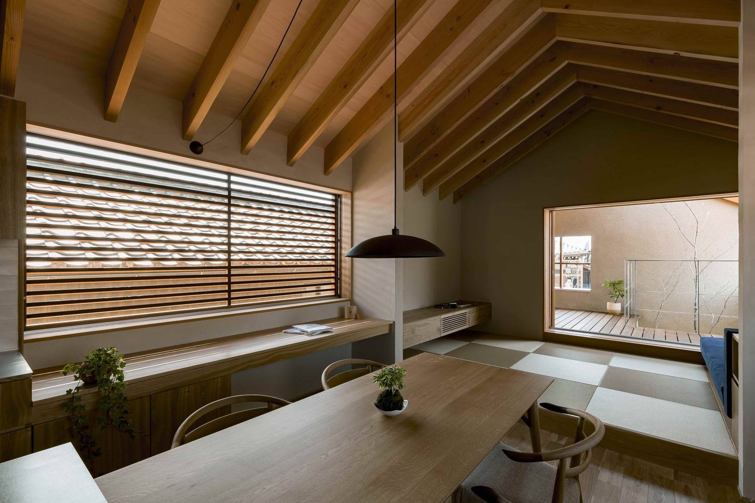 Hình ảnh phòng phòng ăn thoáng sáng với trần ốp gỗ, bàn ghế gỗ, đèn thả trang trí, ghế ngồi bên cửa sổ