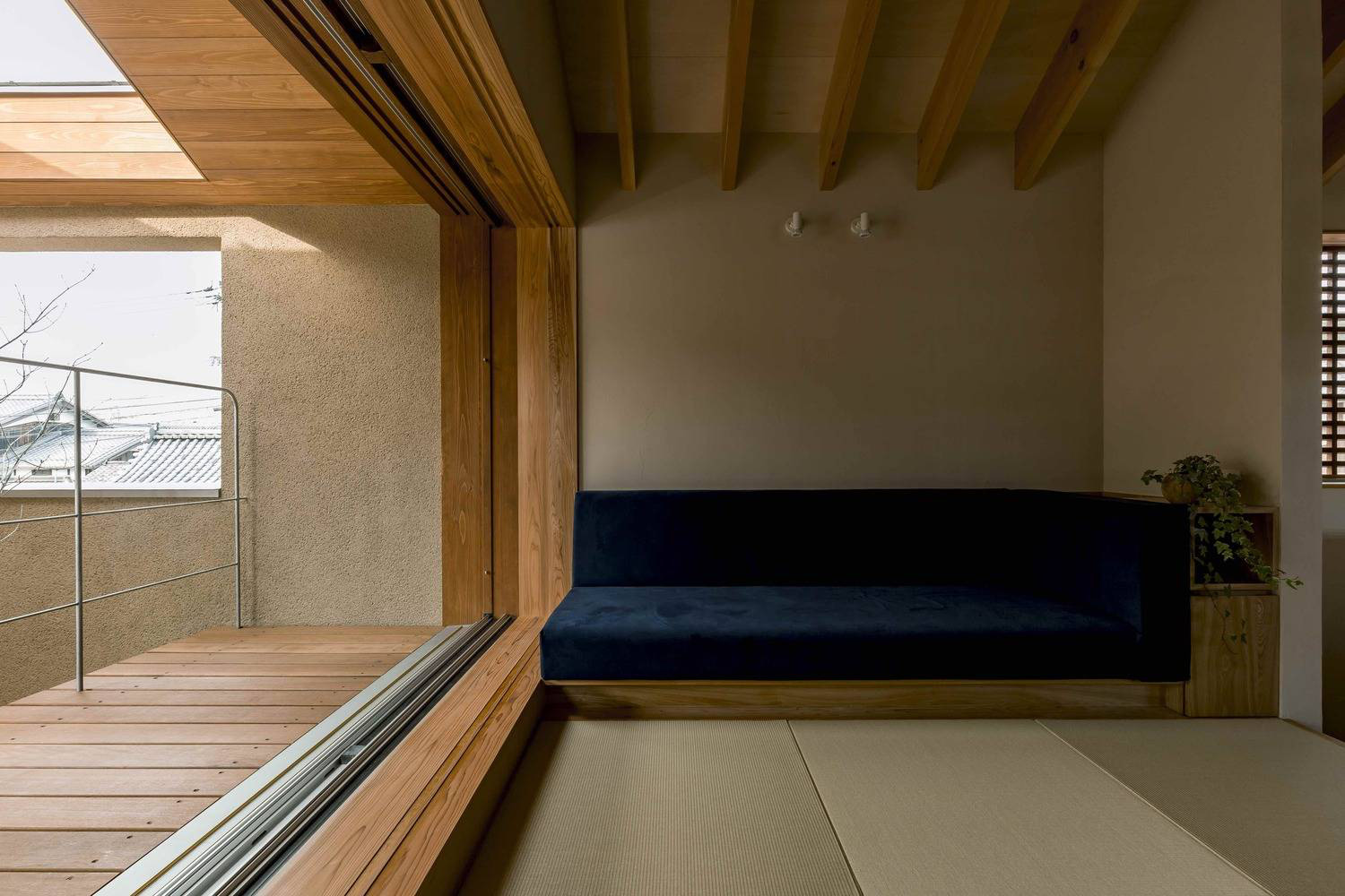 Hình ảnh một căn phòng trong nhà phố, nổi bật với sofa lót đệm xanh dương, lan can sắt, sàn lát gỗ