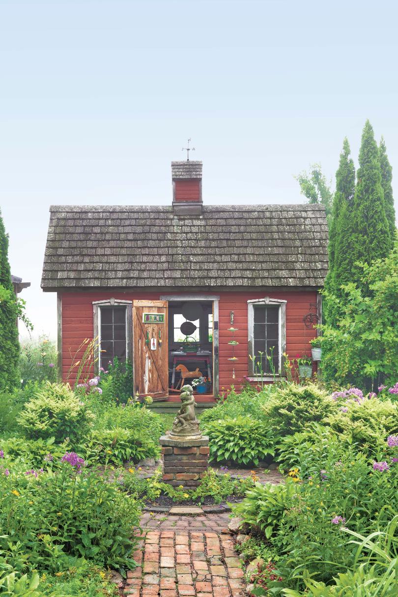 Hình ảnh toàn cảnh một ngôi nhà gỗ sơn đỏ tọa lạc giữa khu vườn xanh mướt kiểu Anh
