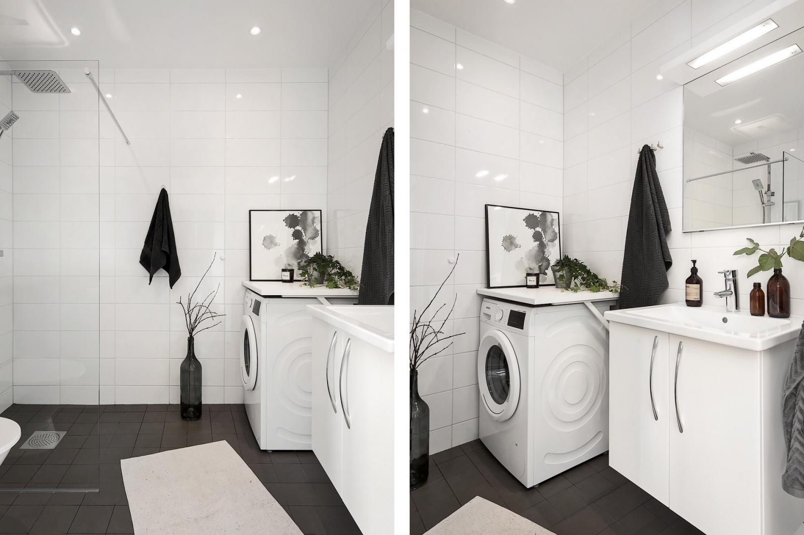 Hình ảnh phòng tắm màu trắng chủ đạo với sàn lát gạch màu đen, trang trí bằng tranh tường, cây xanh
