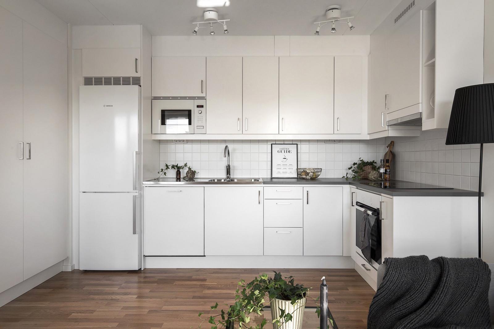 Hình ảnh hệ tủ chữ L màu trắng tinh khôi như hòa lẫn vào không gian tổng thể, nơi lưu trữ thiết bị nấu nướng, vật dụng phòng bếp.
