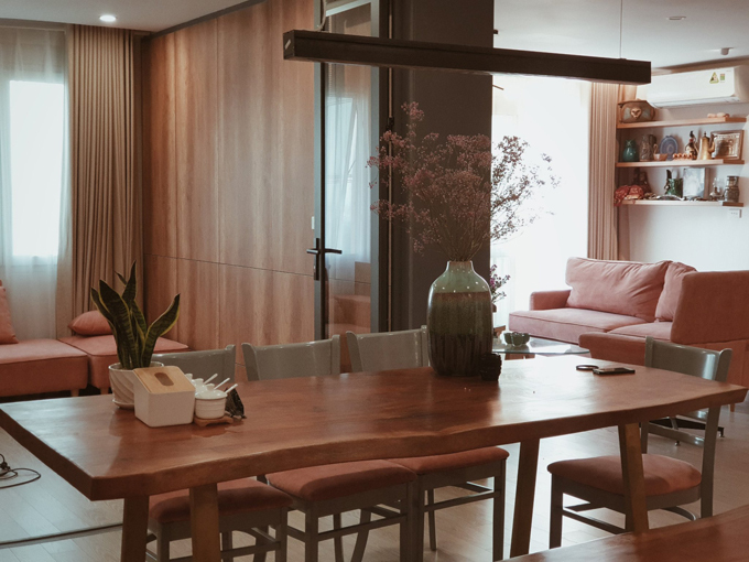 Hình ảnh phòng ăn ấm cúng với bàn dài bằng gỗ trong căn hộ tông màu hồng san hô của Lek Chi