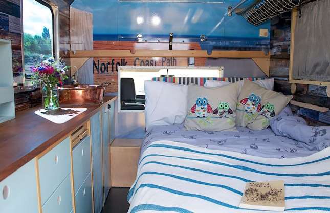 Hình ảnh bên trong ngôi nhà di động cải tạo từ xe cứu thương gồm giường ngủ đặt cạnh bếp, cửa sổ kính trong suốt