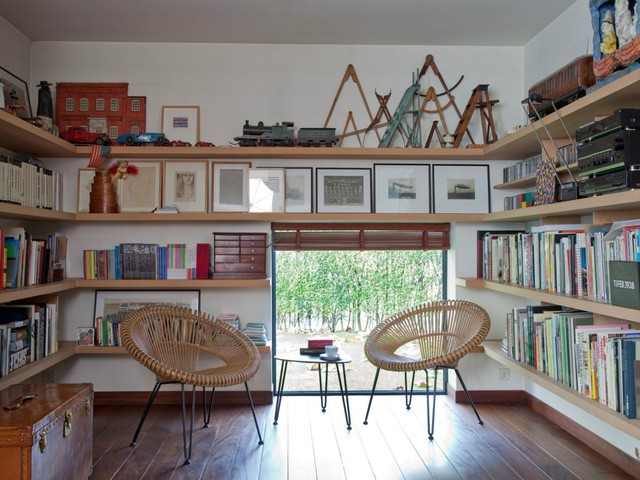 Hình ảnh phòng khách độc đáo với hai ghế ngồi bằng mây tre đan, xung quanh là giá kệ lưu trữ gắn tường