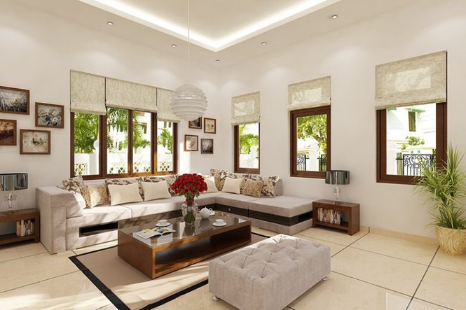 Hình ảnh trong phòng khách, kiến trúc sư bố trí nội thất đơn giản với ghế sofa chữ L lớn, bàn trà gỗ hình chữ nhật, sử dụng tranh treo tường và cây xanh tạo điểm nhấn.