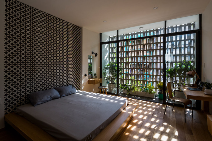Hình ảnh phòng ngủ đơn giản với giường phản, bàn trang điểm, bàn làm việc gắn tường, hoa nắng trên sàn nhà