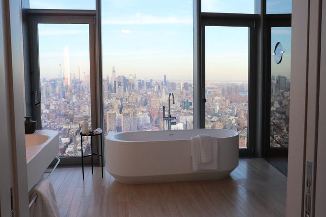 Hình ảnh phòng tắm sang trọng với bồn tắm lớn màu trắng đặt cạnh cửa sổ kính