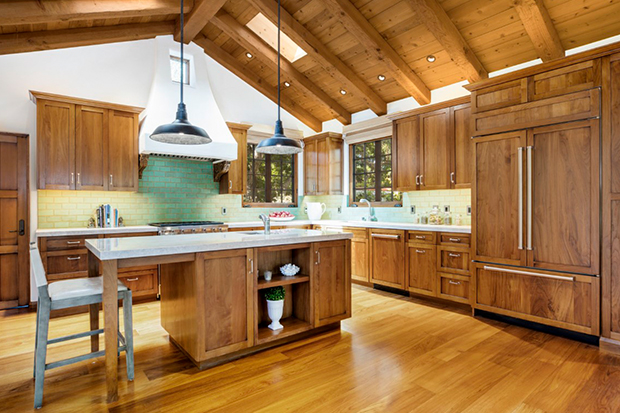 Hình ảnh phòng bếp ấm cúng với tủ lưu trữ bằng gỗ, tường sơn trắng, đảo bếp trung tâm với đèn thả trang trí